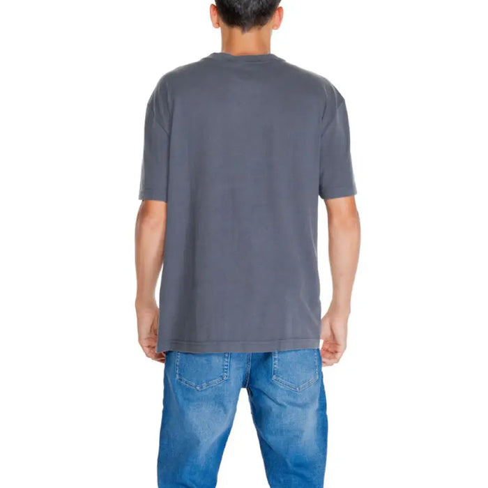 Back view of a person in a gray Calvin Klein T-shirt and blue jeans