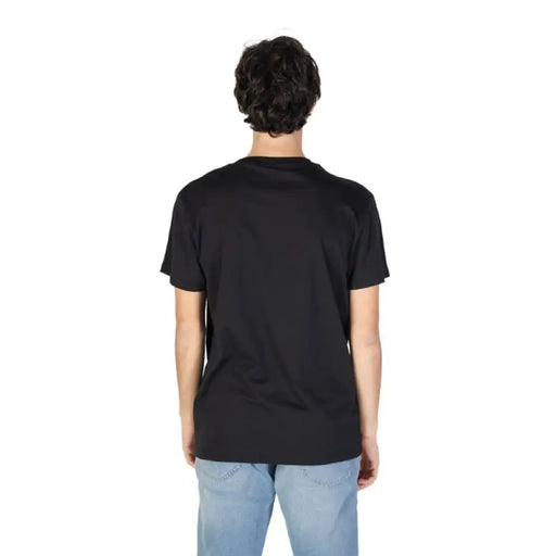 Back view of a person in a black t-shirt and light blue jeans for Moschino Underwear