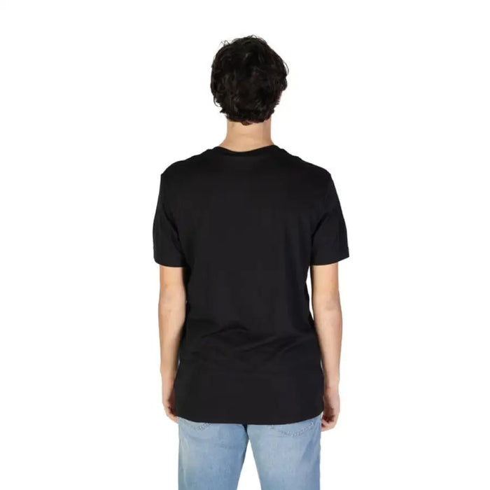 Back view of a model in a black t-shirt and light blue jeans for Calvin Klein Jeans