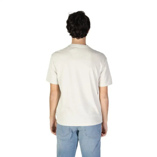 Back view of a person in a Gas Men T-Shirt with light blue jeans