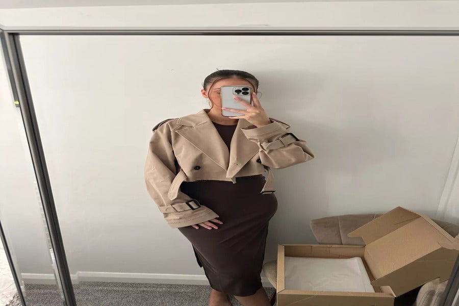 Person in beige blazer and brown skirt taking mirror selfie for style inspiration.