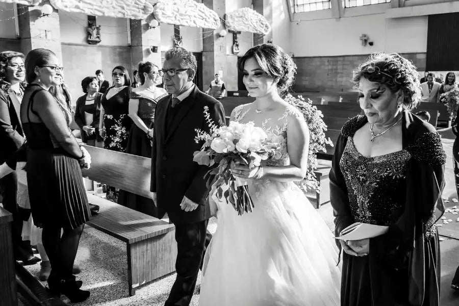 Bride in white dress holding bouquet during wedding ceremony for style guide article