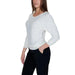 Model wearing Guess Women Knitwear: white long-sleeved top paired with black pants