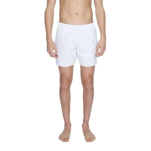 White men’s boxer shorts worn by a shirtless model, Ea7 Men’s Swimwear