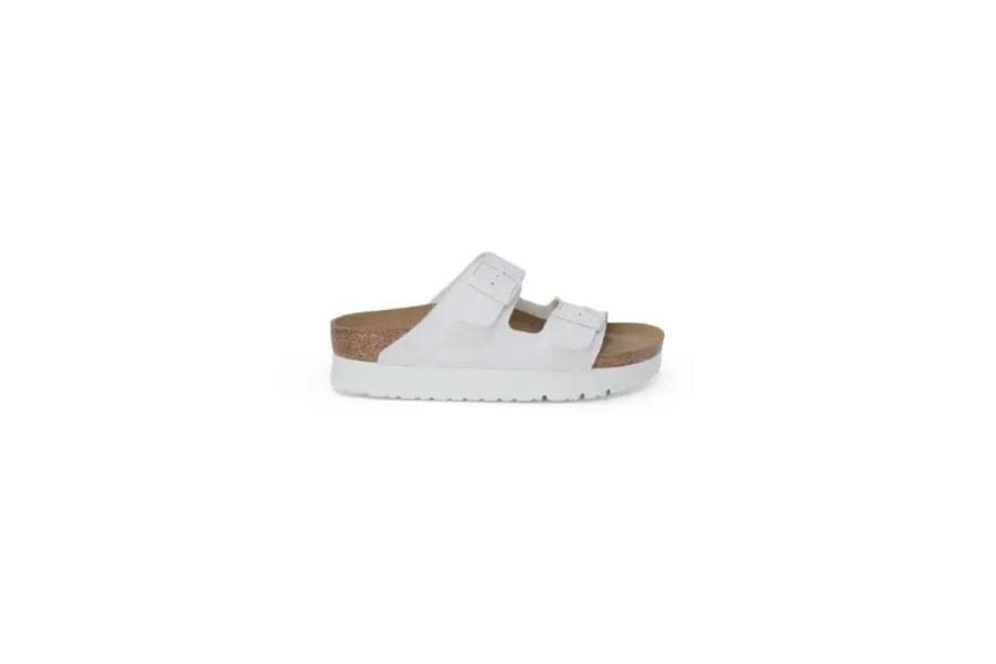 White slip-on sandal with cork-like footbed and buckle strap for a versatile capsule wardrobe.