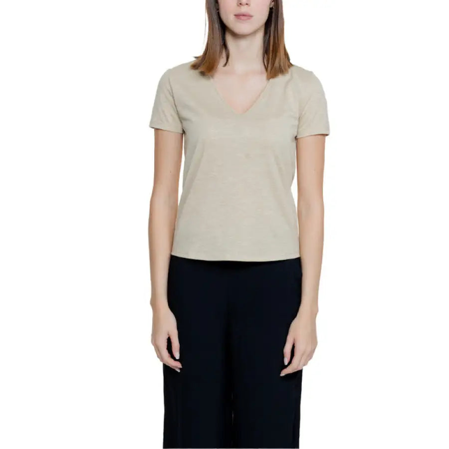 Woman in beige v-neck t-shirt by Jacqueline De Yong, paired with dark pants