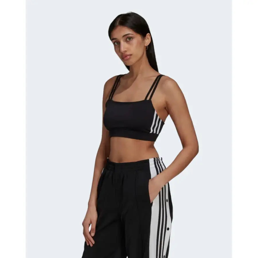 Woman in black Adidas crop top and pants with white stripes, from Adidas Women Undershirt collection