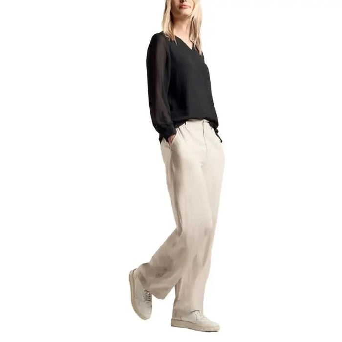 Woman in black top and beige wide-leg pants styled with sneakers from Street One