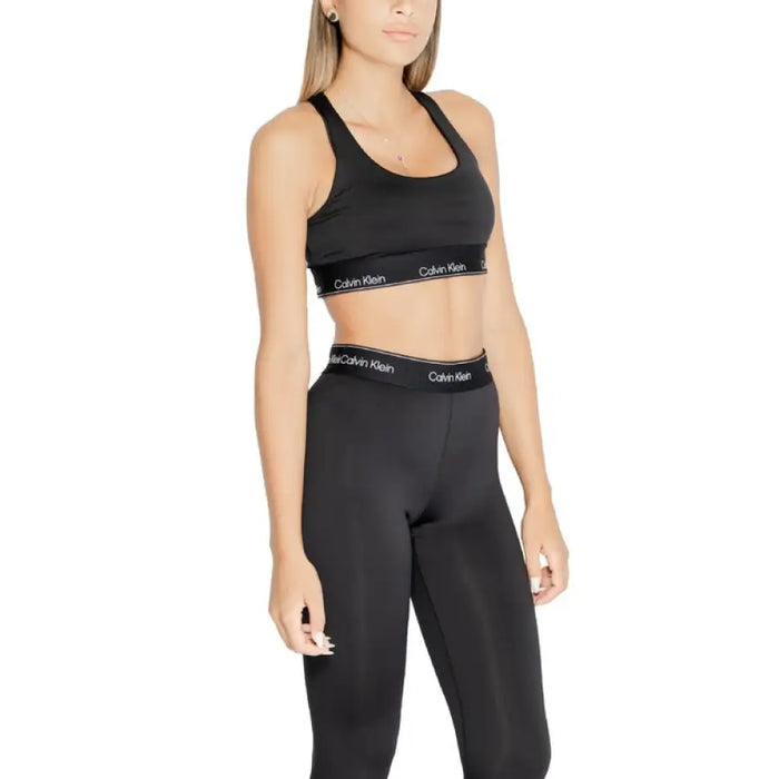 Woman modeling black Calvin Klein sports bra and leggings from Calvin Klein Sport collection