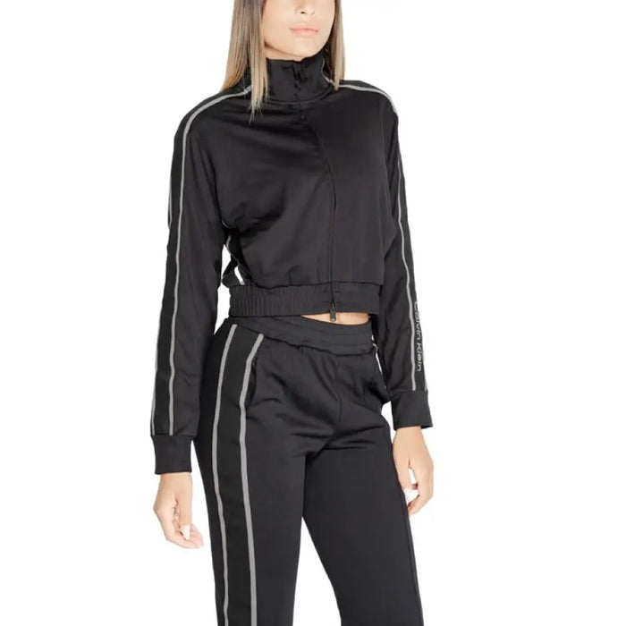 Woman modeling a black cropped turtleneck sweatshirt with gray side stripes by Calvin Klein Sport