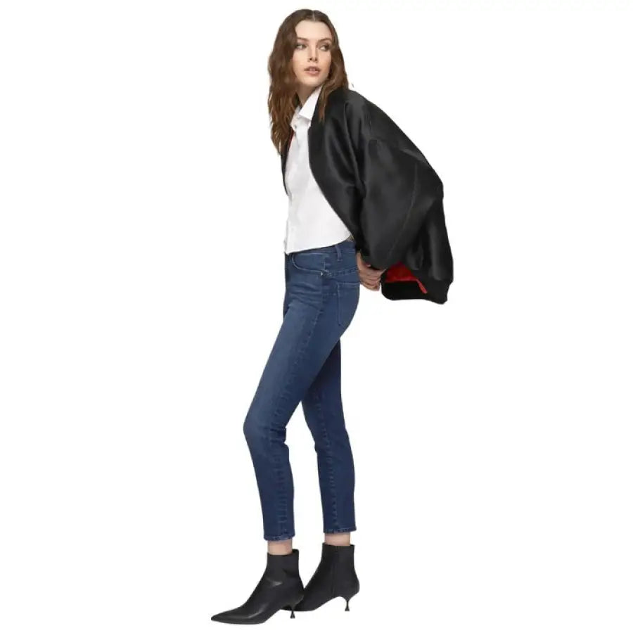 Stylish woman in black jacket, white top, blue jeans, and black ankle boots - Gas Jeans