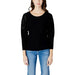 Guess women knitwear, model in Guess black top and jeans posing stylishly