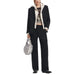 Woman in a black pantsuit with light top and silver sequined handbag by Desigual