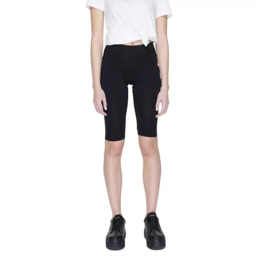 Woman modeling Icon Men Shorts in black, paired with a white shirt