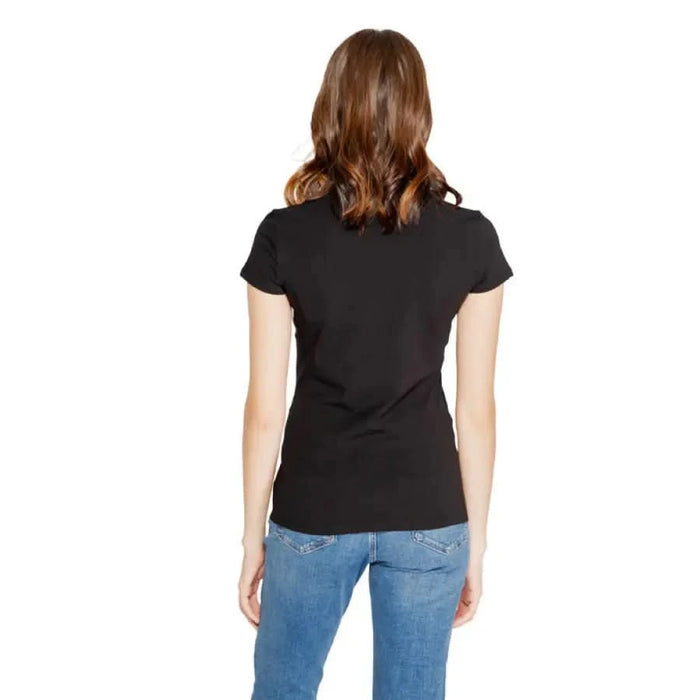 Woman in a black t-shirt and blue jeans from behind, showcasing Armani Exchange style