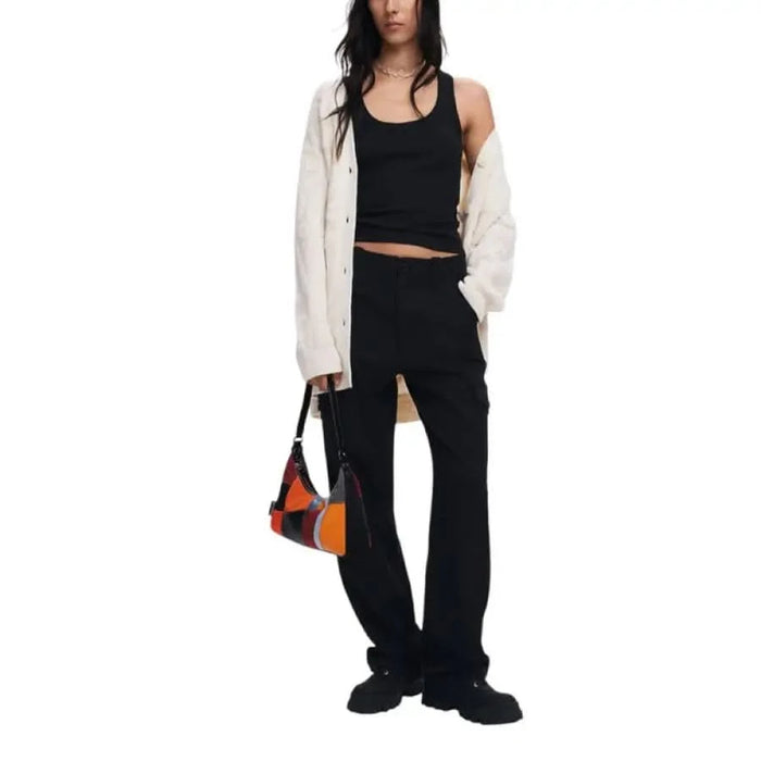 Woman in black tank top and pants with white Desigual cardigan and colorful handbag