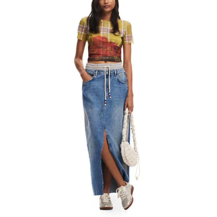 Woman in colorful crop top and long denim skirt with white sneakers and handbag