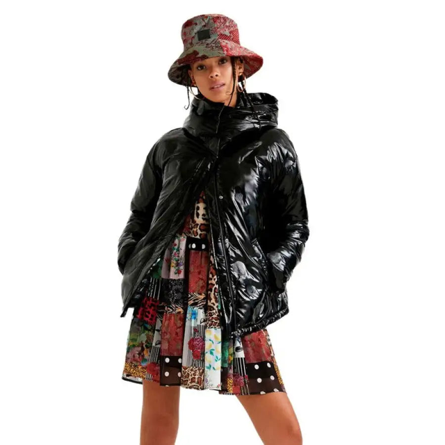 Woman in Desigual shiny black puffer jacket, colorful dress, and red patterned bucket hat