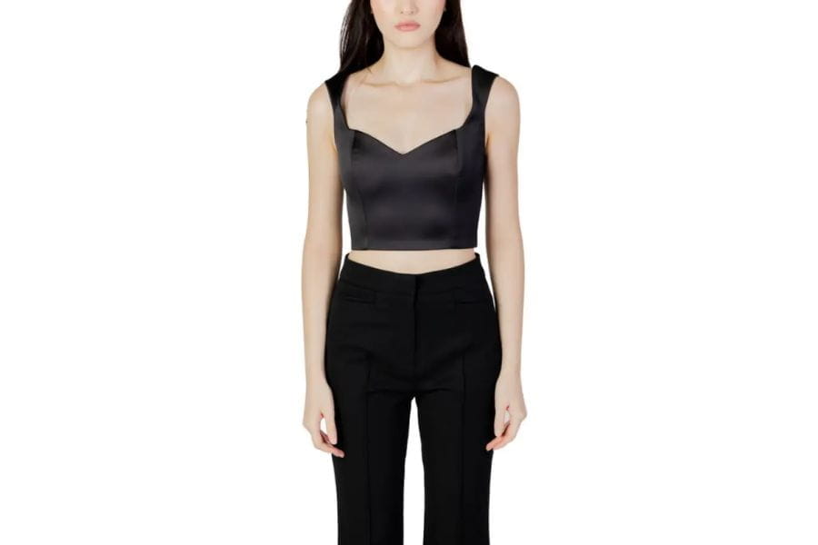 Woman in a black crop top and high-waisted pants, stylish holiday outfit idea.