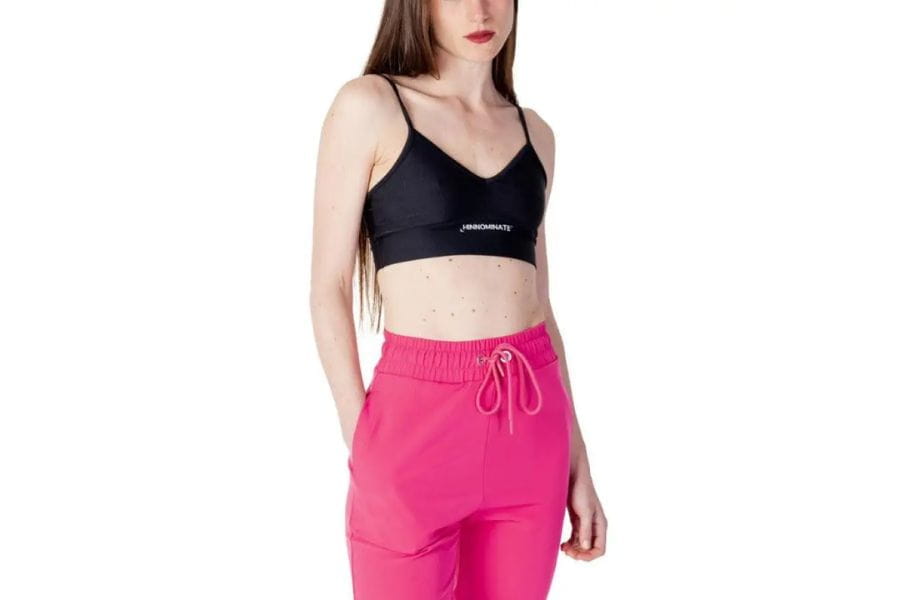 Woman in a black sports bra and bright pink pants showcasing holiday outfit options.