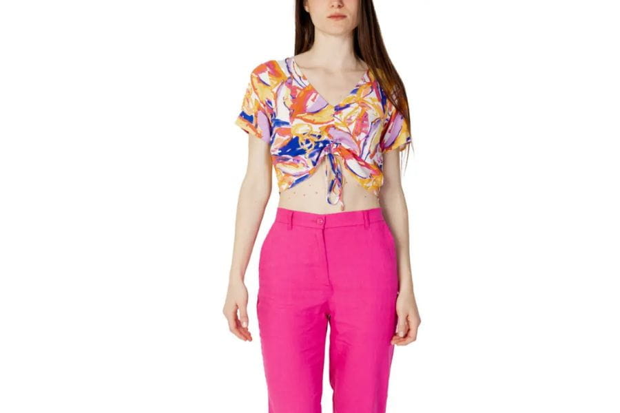 Woman in floral crop top and pink pants showcasing vibrant holiday outfits.