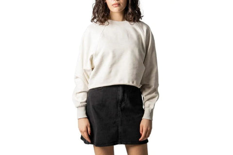 Woman in a cream sweater and black skirt showcasing summer work outfits for the office.