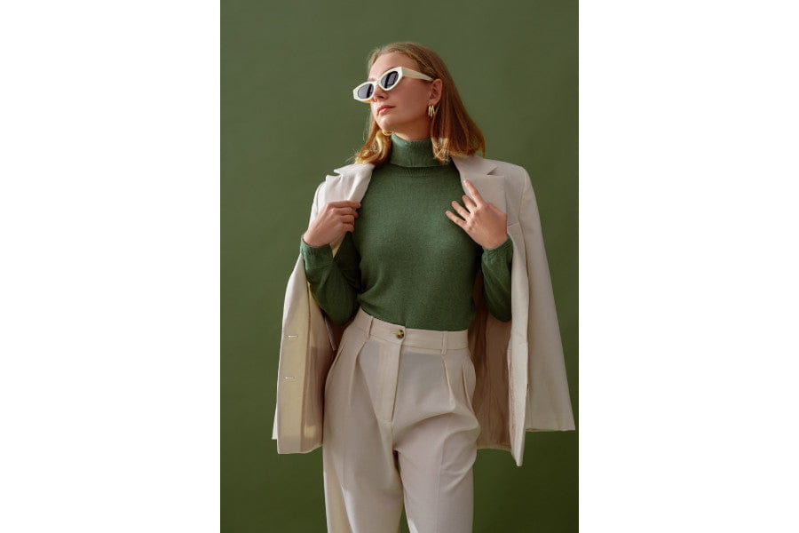 Woman in green turtleneck and white pants showcases old money style for an elegance look.