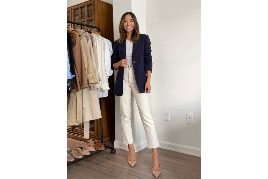 Woman in navy blazer and white pants, showcasing stylish minimalist apparel.