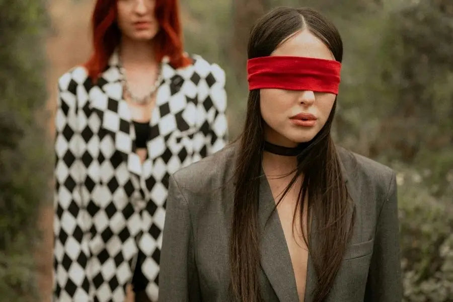 Woman in a red blindfold and dark jacket showcasing retro fashion style.