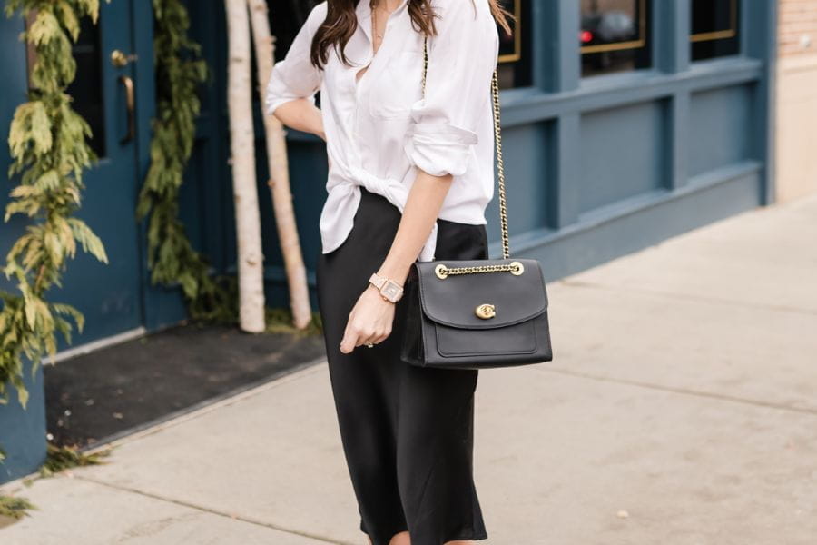 Woman in a white blouse and black pants showcasing chic summer work outfits.