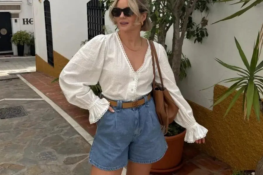 Woman wearing a white blouse and blue denim shorts for a perfect summer outfit idea.