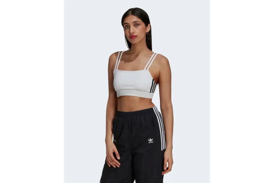 Woman in a white crop top and black Adidas track pants for summer outfit ideas.