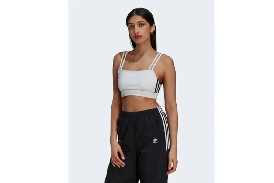 Woman in white sports bra and black track pants, ideal holiday outfit for active wear.