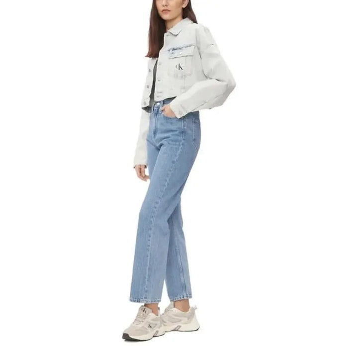 Woman in white denim jacket, light blue jeans, and white sneakers - Calvin Klein Jeans