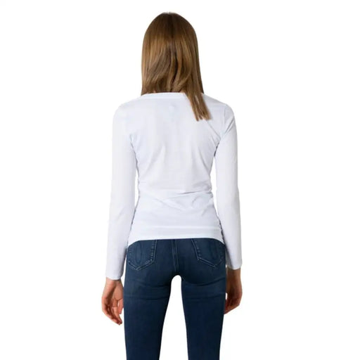 Woman in a white long-sleeved shirt and blue jeans, showcasing Armani Exchange style