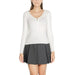 Woman in white long-sleeved top and dark pleated miniskirt from Morgan De Toi Knitwear