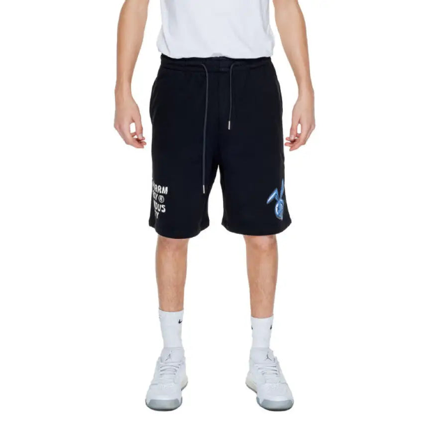 Young man wearing white t-shirt and black Pharmacy Men Shorts from Pharmacy